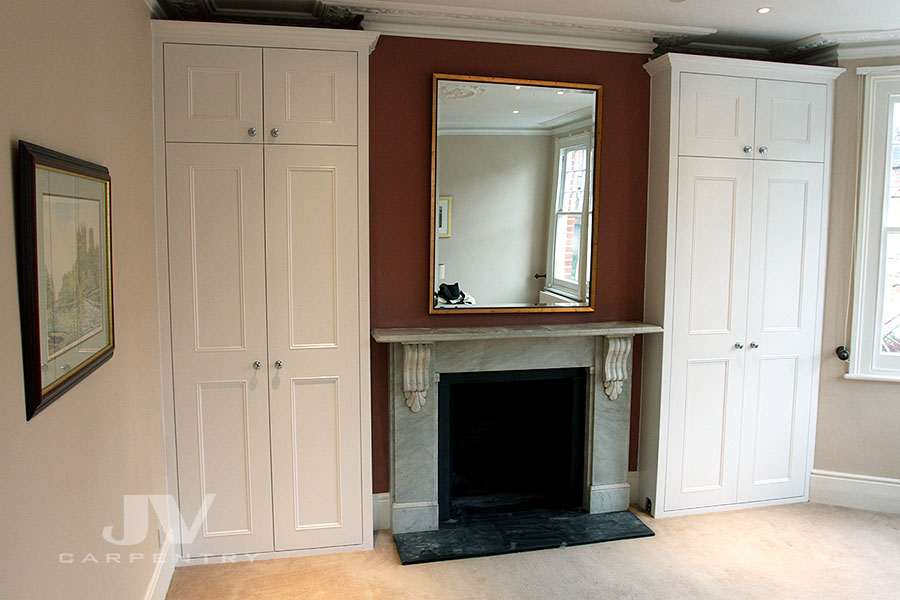 Two alcove wardrobes traditioanl style either side of the chimney breast.